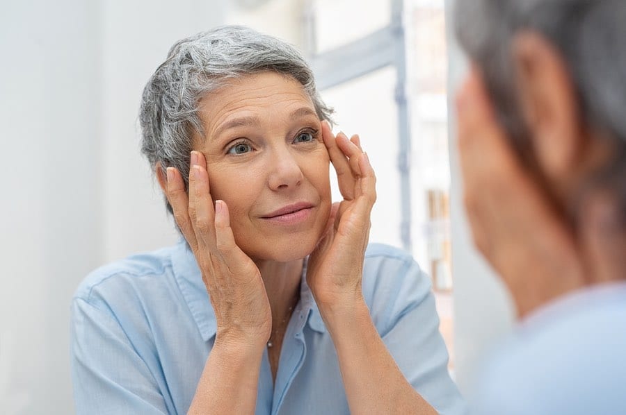 Senior woman looking in mirror after taking Hyalogic® Hylavision 