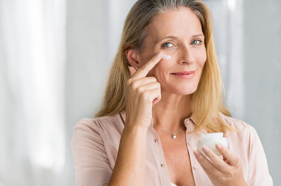 Smiling senior woman applying Hyalogic® anti-aging lotion