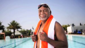 Older man smiling by swimming pool